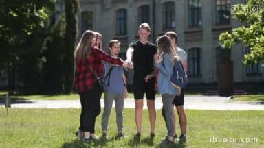 快乐的青少年朋友手拉着手，站在大学校园公园的草坪上，快乐的学生群在堆